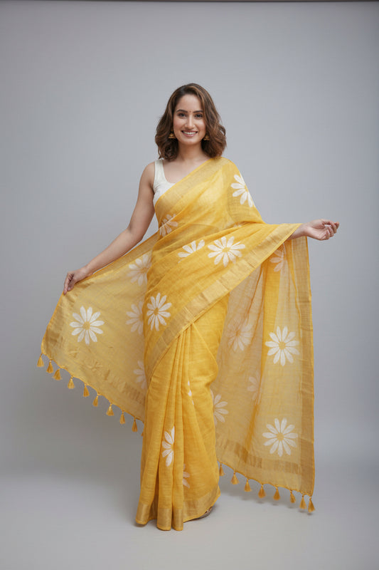 Woman wearing a yellow saree with white floral patterns on a plain background