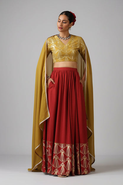 Woman wearing a traditional outfit with a gold blouse and red skirt against a plain background