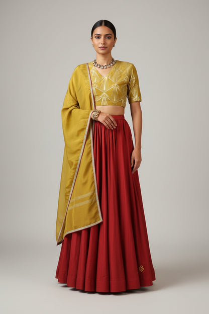 Woman wearing a mustard yellow blouse with red pleated skirt on a beige background