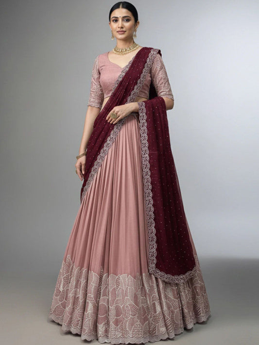 Woman wearing a pink saree with maroon border on a gray background