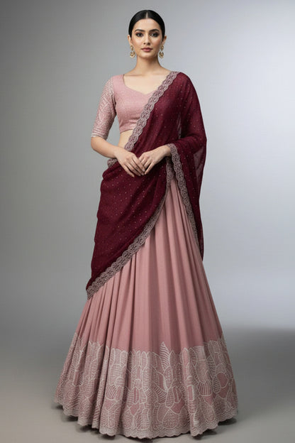 Woman wearing a pink saree with a maroon blouse and saree cover on a gray background